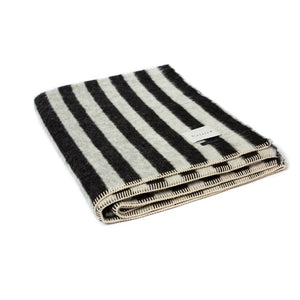 The Blacksaw Stills Vertical Stripe Blanket in Black/Ivory, folded product shot with beautiful Blanket Stitching and branded label
