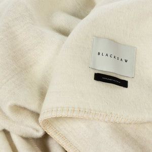 The Blacksaw  100% Alpaca, Reversible TimeWarp Throw Blanket in    Zero Dye Ivory & Shoj  Close Up product shot showing beautiful brand label and Blanket Stitching detail