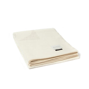 The Blacksaw 100% Alpaca, Reversible TimeWarp Throw Blanket in  Zero Dye Ivory & Shoji, folded product shot with beautiful Blanket Stitching and branded label