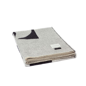 The Blacksaw 100% Alpaca, Reversible TimeWarp Throw Blanket in Black and Ivory, folded product shot with beautiful Blanket Stitching and branded label