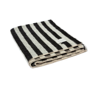 The Blacksaw Stills Vertical Stripe Blanket in Black/Ivory, folded product shot with beautiful Blanket Stitching and branded label 