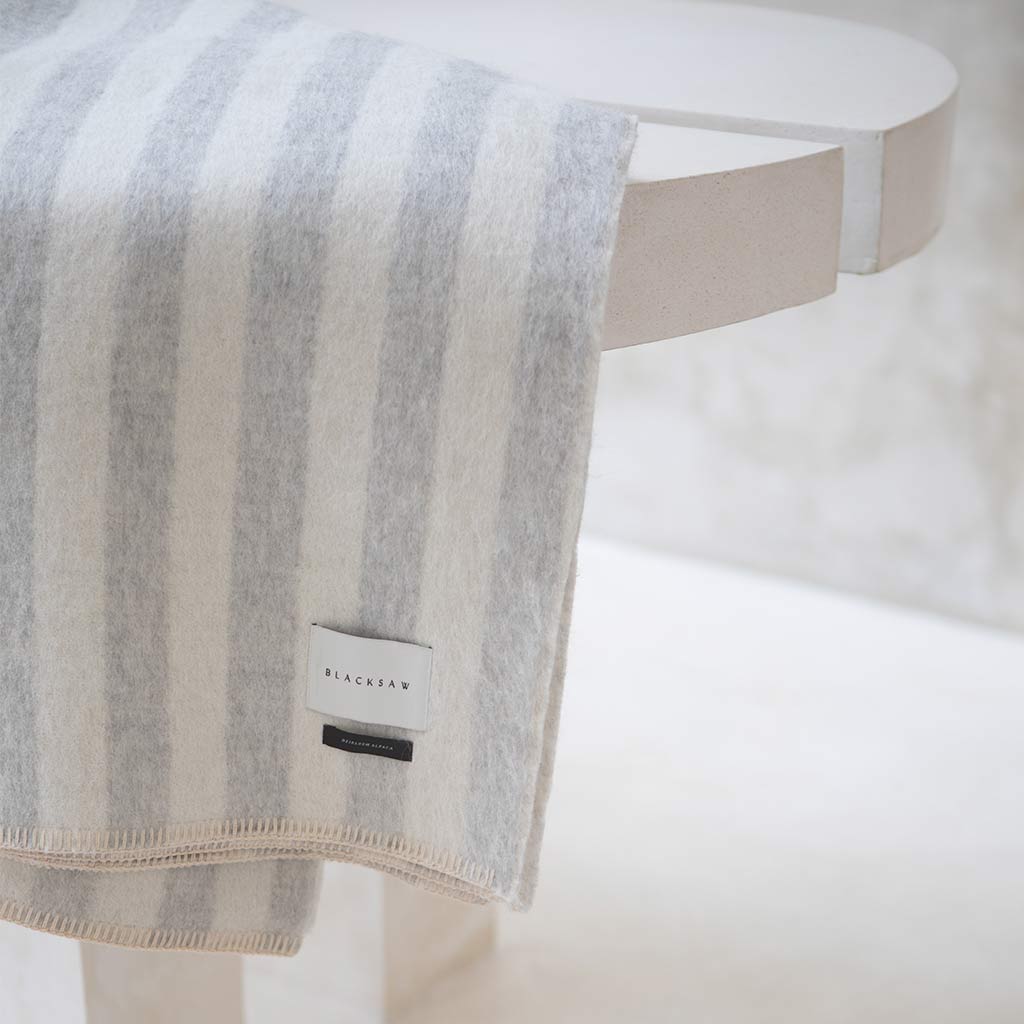 The Blacksaw Stills Vertical Stripe Blanket in Light heather Grey/Ivory Flat laying product shot