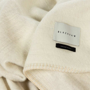 The Blacksaw  100% Alpaca, Reversible TimeWarp Throw Blanket in    Zero Dye Ivory & Shoj  Close Up product shot showing beautiful brand label and Blanket Stitching detail