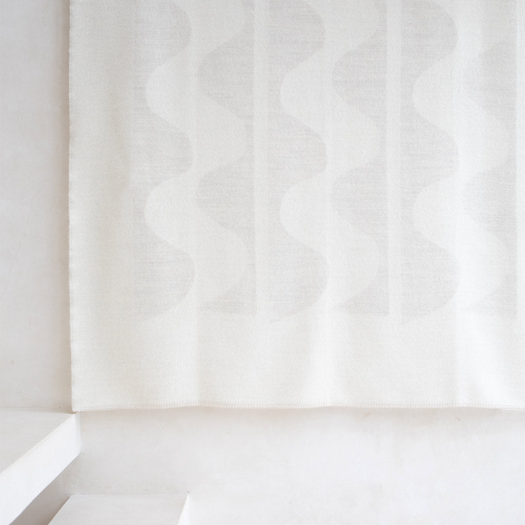 The Blacksaw 100% Alpaca, Reversible TimeWarp Throw Blanket laying flat in Zero Dye Ivory & Shoji. 